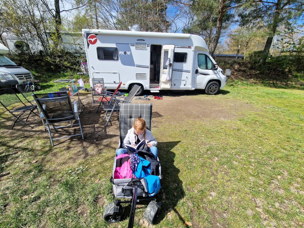 Familie mit Kinderwagen am Wohnmobil auf einem Campingplatz